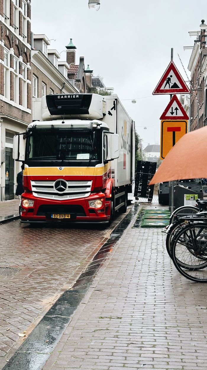 Services Delivery truck navigating a rainy Amsterdam street, highlighting urban logistics.